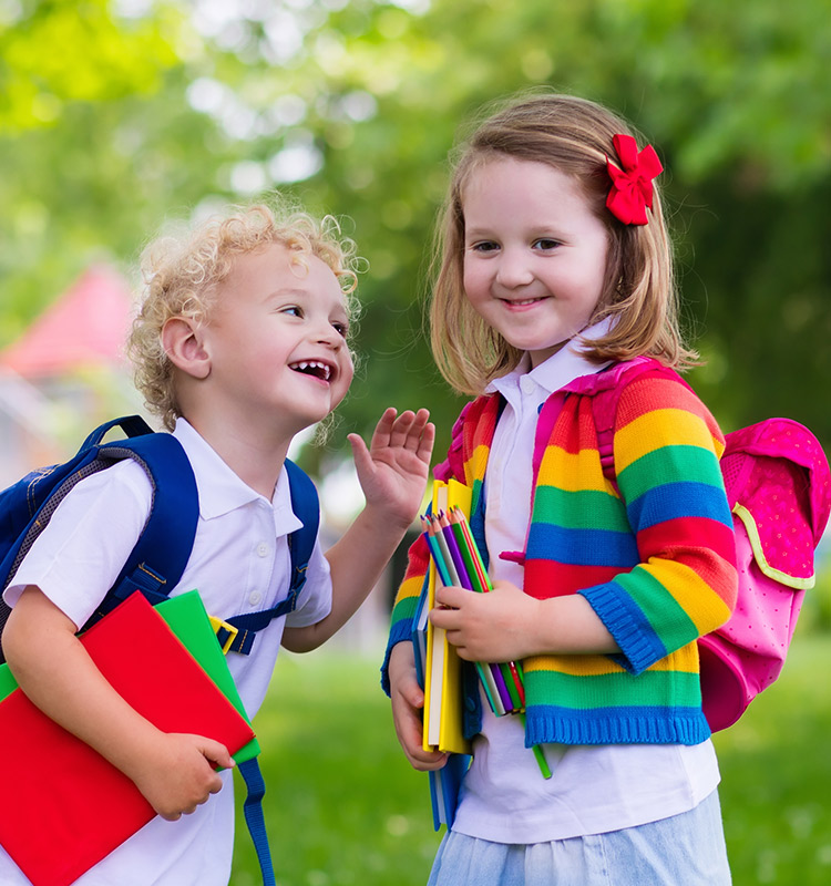 Zwei Schulkinder in bunter Kleidung mit farblich passenden Schulranzen.